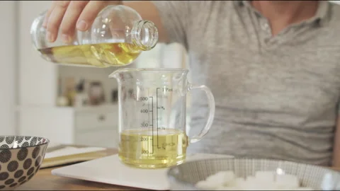 Filling measuring cup with oil Stock Footage 135639876