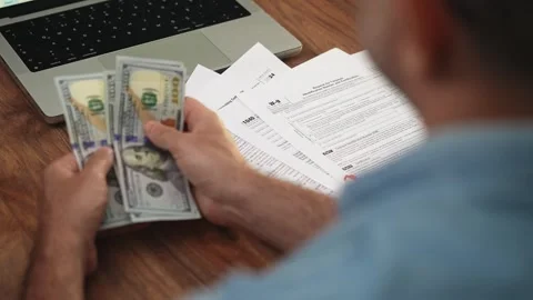 Before filling out tax forms man counts money by transferring dollar bills from Stock Footage 292403190