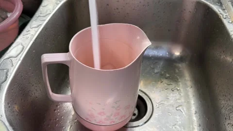 Filling Pink Pitcher with Water at Kitchen Sink Stock Footage 325410507