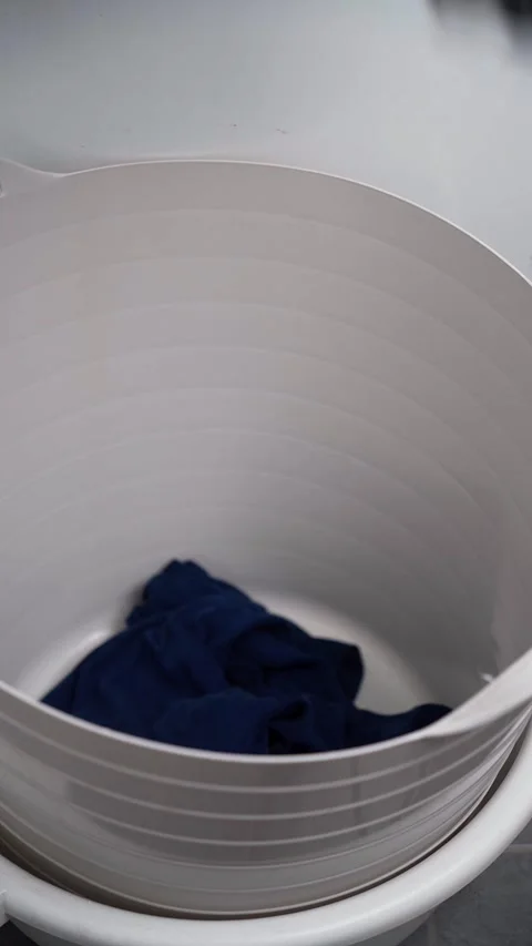 Filling plastic laundry basket with clothes Stock Footage 333583705