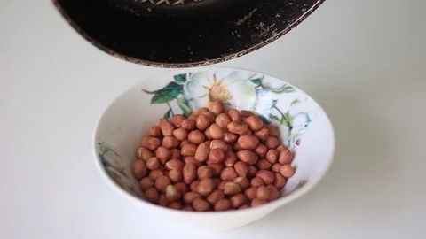 Filling a plate with roasted peanuts from a pan Stock Footage 71952878