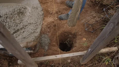 Filling post hole with concrete, expertly filling deep post footing with Stock Footage 319692604