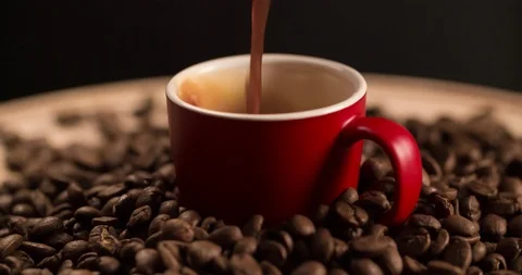 Filling up Red Cup with Black Coffee and scattered coffee beans rotating Stock Footage 98267095