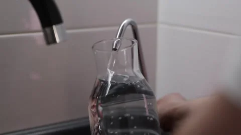Filling reusable glass bottle with fresh filtered water from kitchen tap Stock Footage 339794785