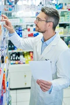 Filling the script to fit my clients pocket. a mature pharmacist working in a Stock Photos