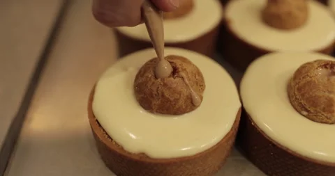Filling small eclairs with cream using a culinary syringe Stock Footage 254813442
