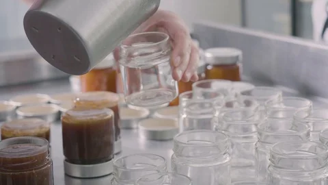 Filling small jars of homemade jam Stock Footage 129993337