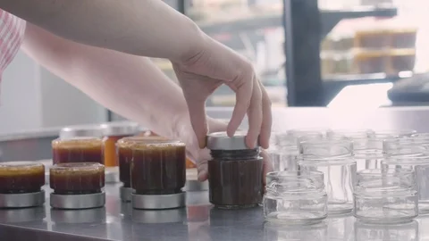 Filling small jars of homemade jam Stock Footage 129993339