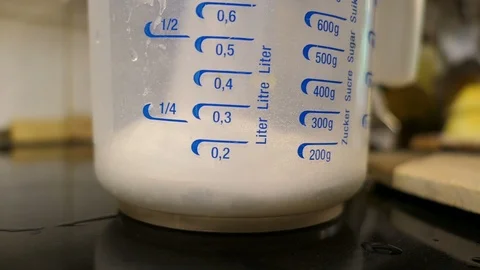 Filling sugar into a kitchen measuring cup 스톡 동영상 109378654