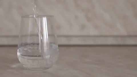 Filling a transparent glass on the kitchen table with water. Stock Footage 150681648