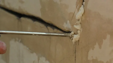 Filling a wall crack with foam Stock Footage 128418480