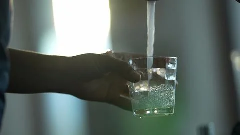 Filling water into glass cup from faucet tap water Stock Photos