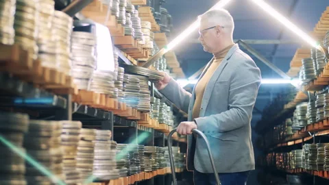 Film expert is inspecting old movie cases while standing on a ladder Vídeo Stock 158359945