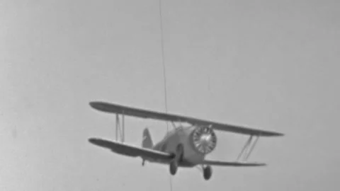 From a film reel capturing a single-engine biplane in flight against a pale Stock Footage 341373061