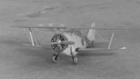 From a film reel showing a single-engine biplane idling on a dirt or grass Stock Footage 341899245