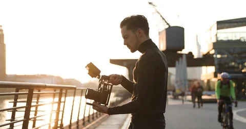 Filmmaker camera handheld on sunset in a big city. People run in background Stock Footage 126862018
