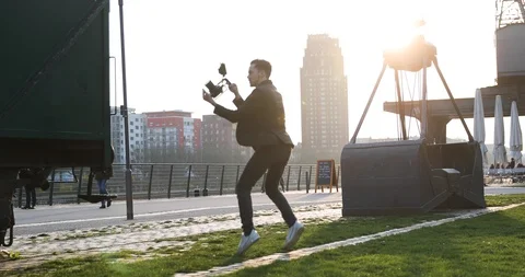 Filmmaker jump with the camera handheld on sunset in a big city. Industrial Stock Footage 126860975