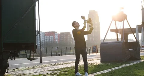 Filmmaker jump with the camera handheld on sunset in a big city. Industrial Stock Footage 126862527