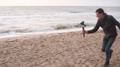 Filmmaker shoot video on camera with electronic stabilizer on the beach Stock Footage 164865221