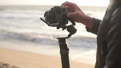 Filmmaker shoot video on camera with electronic stabilizer on the beach Stock Footage 164866391