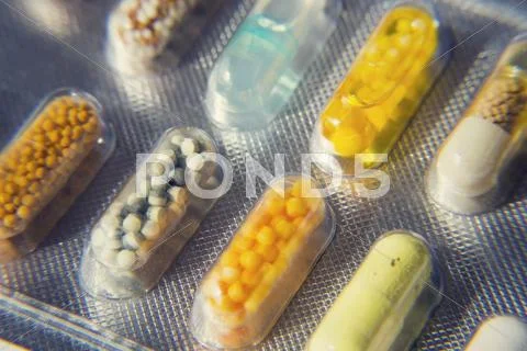 Filtered colorful pills in transparent medicine capsule Stock Photos
