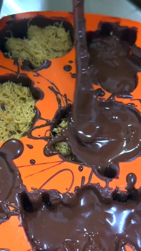 Final chocolate layer covers kunafa filling in spooky silicone mold. Glossy Stock Footage 343478606