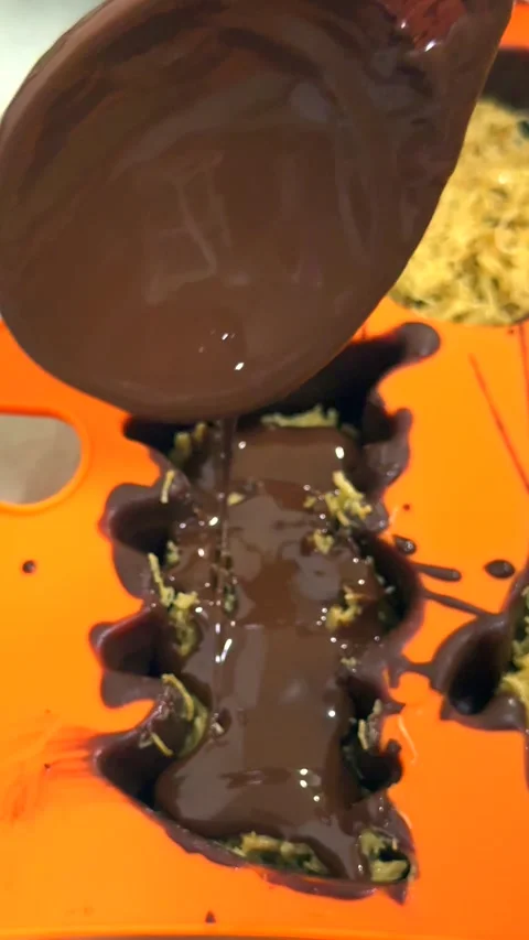Final layering step in DIY chocolate candy craft. Melted chocolate is poured Stock Footage 343478557