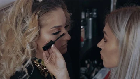 The final stage of makeup. Make-up artist applies mascara on the blonde's Stock Footage 157604323