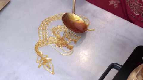 Final syrup threads finish a golden sugar dragon sculpture 4/6 Stock Footage 341514934