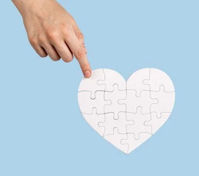 The final touch. Placing the missing puzzle piece to heart-shaped jigsaw Stock Photos