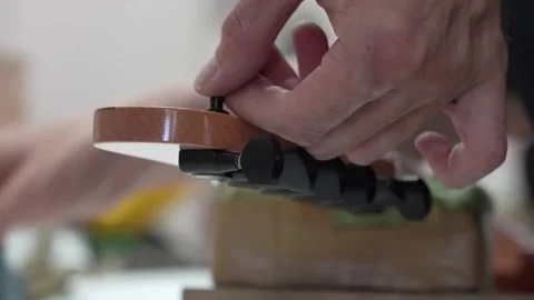 Finalizing the headstock of a guitar by tuning a string Stock Footage 317138236