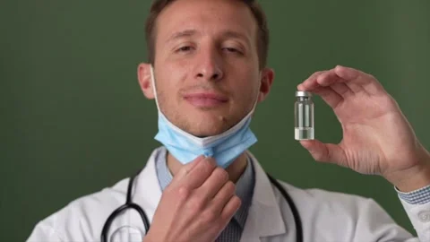 Finally. Young male therapist taking off protective mask while holding a vial of Stock Footage 147961453