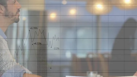 Finance analyst writing on paper showing graph overlay tracking bars, dips, Stock Footage 313554796