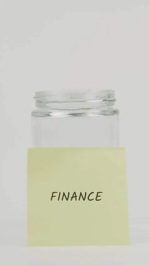 Finance text or word on yellow sticky note attached to glass jar with hand Stock Footage 311732904