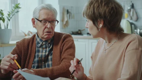 Financial Advisor Discussing Documents with Elderly Man at Home Stock Footage 265382797