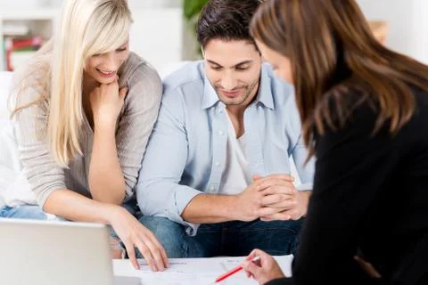 Financial advisor explaining document to couple at table Stock Photos