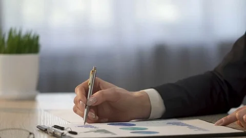 Financial analyst comparing company statistics and making notes on graphs Stock Footage 79928864