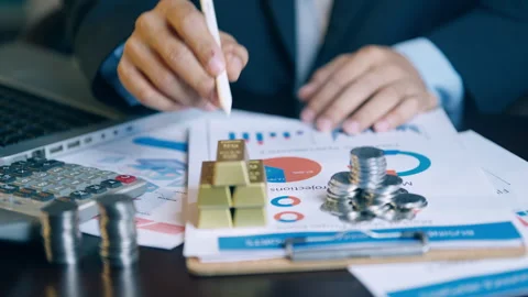 Financial analyst using a pen to check and count gold bars and coins on inv.. Video stock 345941195