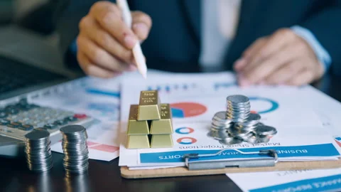 Financial analyst using a pen to check and count gold bars and coins on inv.. Video stock 345941274