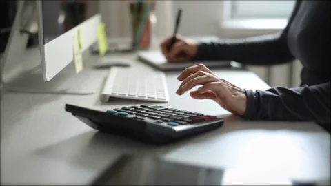 The financial analyst writes the reporting data on the calculator  Stock Footage 117514858