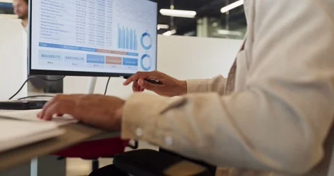 Financial Analyst Writing Notes beside Computer with Charts and Performance Stock Footage 341446728