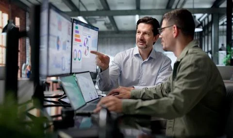 Financial Analysts Discuss Key Performance Data While Working On Laptops Toge Stock Photos