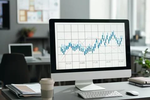 Financial chart and graph on screen of computer standing on desk Stock Photos