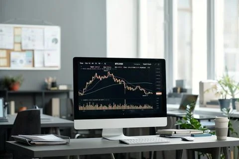 Financial graph and chart on screen of computer standing on workplace Stock Photos