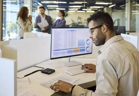Financial manager analyzing spreadsheet charts on desktop computer in office Stock Photos