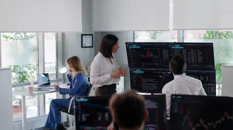 Financial manager discuss graphs on multiple screens with analyst in modern Stock Photos