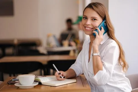 Financial manager writing down in notebook and speak by phone in same time Stock Photos