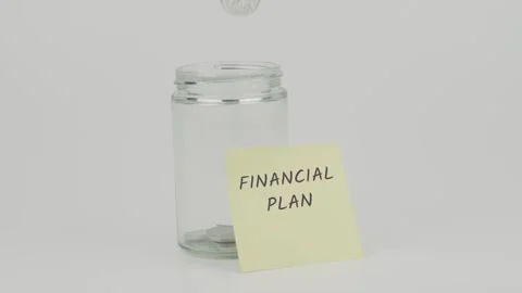 Financial plan text or word on yellow notes on empty jar hand inserting coin Stock Footage 307074688