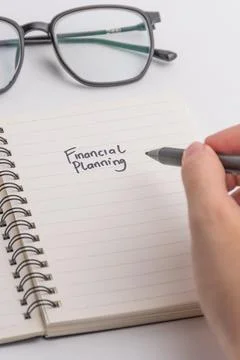 Financial planning concept with spiral notebook eyeglasses and pen isolated.. Stock Photos