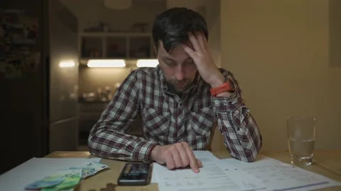 Financial problems. Sad man trying to find solution to taxes and debts at home Stock Footage 225741468